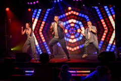 Three vocalists on stage in action
