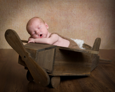 Newborn baby boy in wooden toy aeroplane