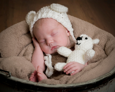 Newborn baby boy fast asleep in bucket